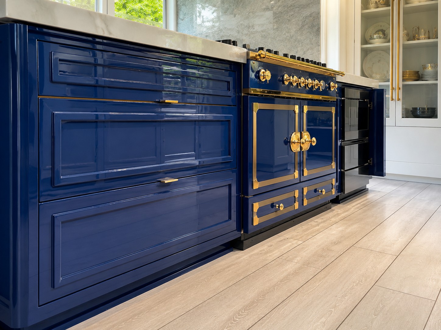 Finished navy high-gloss cabinets with brass pulls beside the La Cornue range