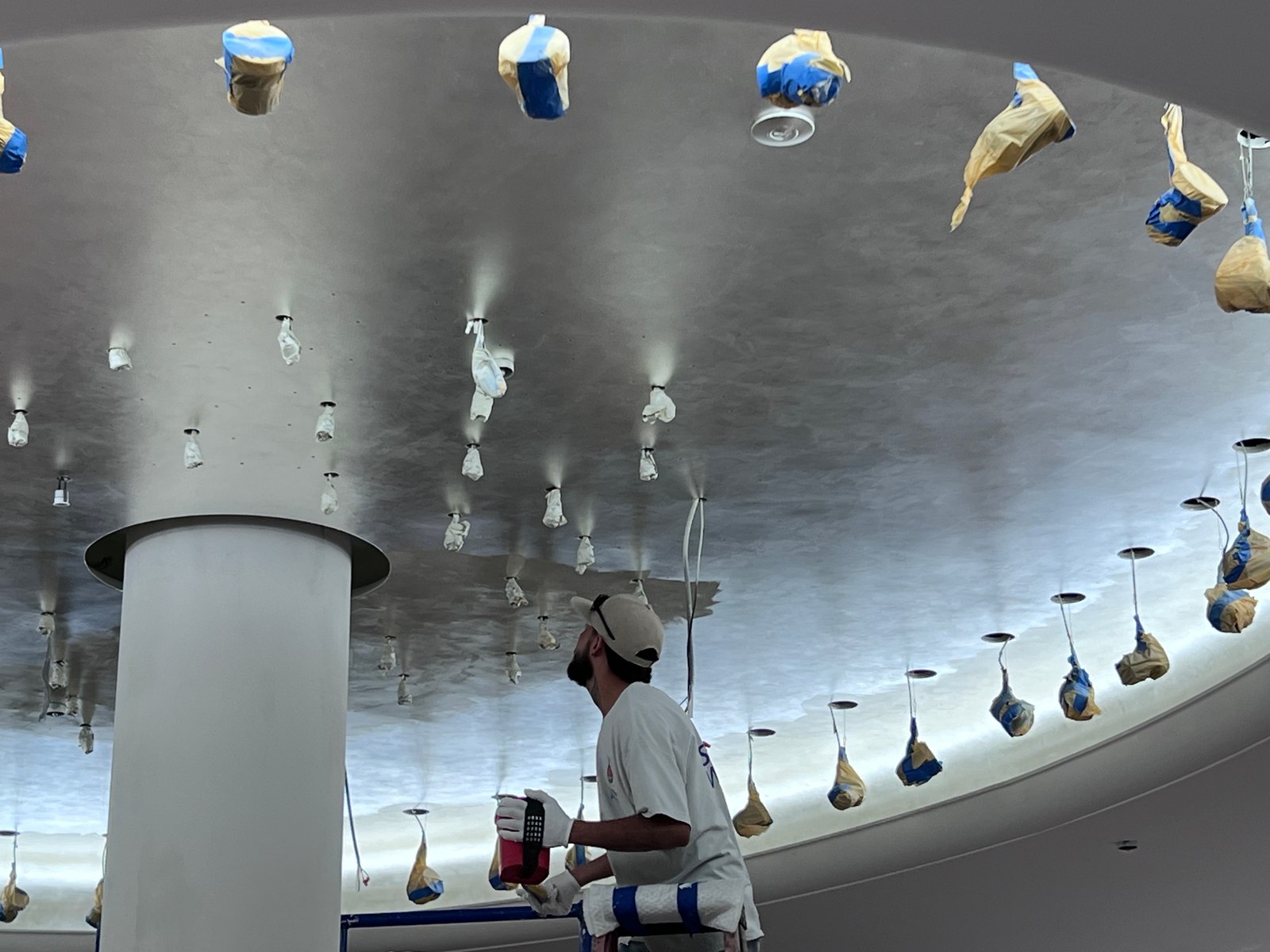 Gold-leaf installation in progress on a ceiling with protected fixtures.