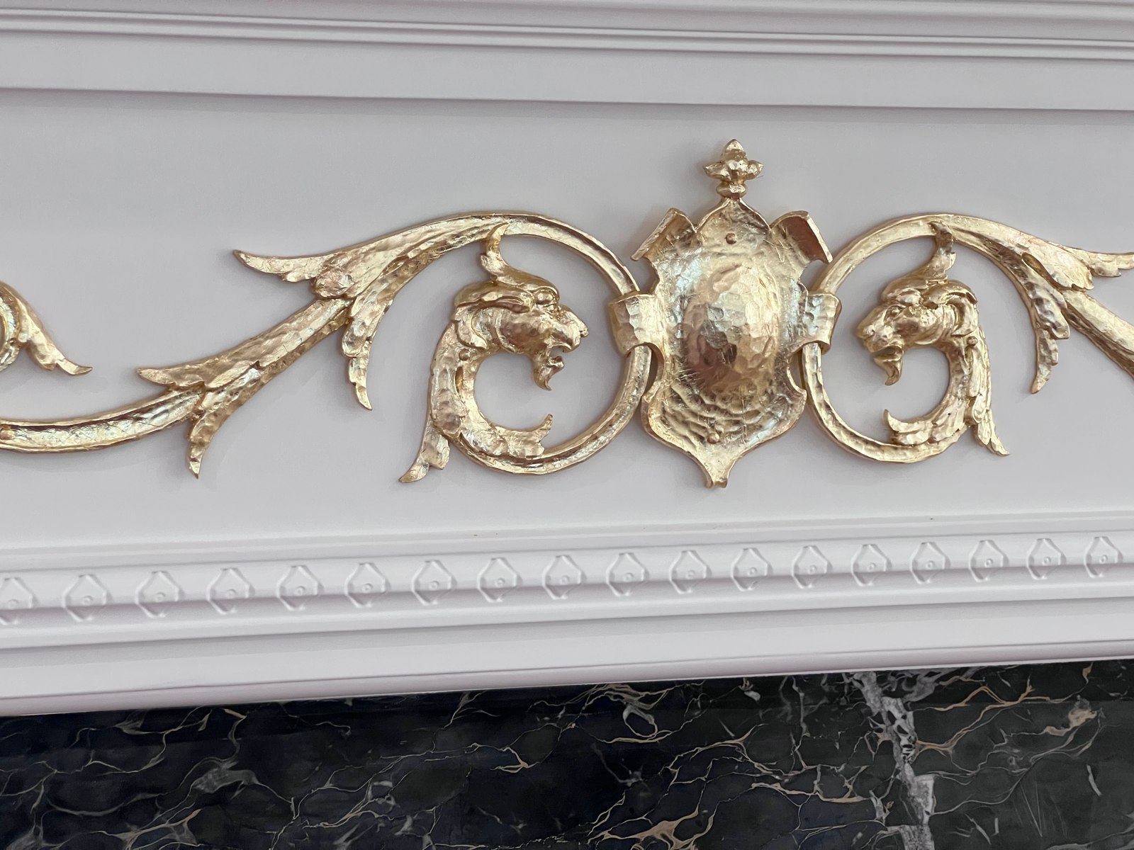 Gold-leaf ornament on a painted fireplace surround.