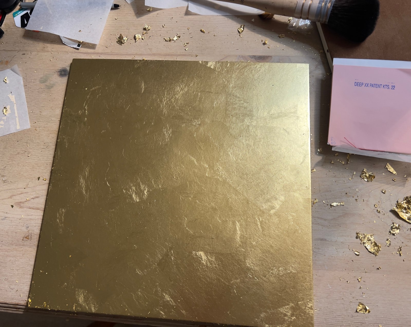 Gold-leaf sample board on a workbench.