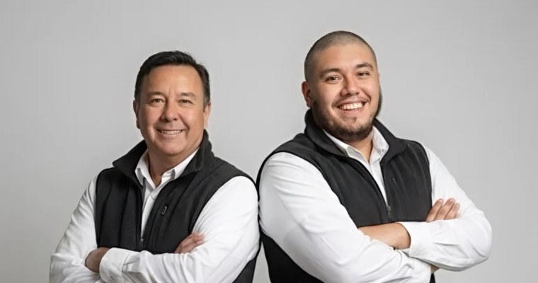 Gabriel and Alex standing together in matching white shirts and dark vests.