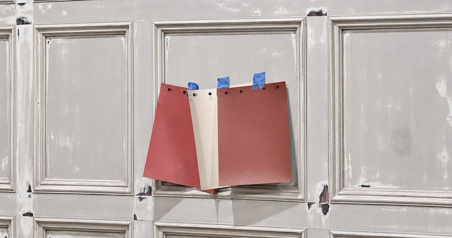 Three color swatches taped to a paneled surface during preparation.