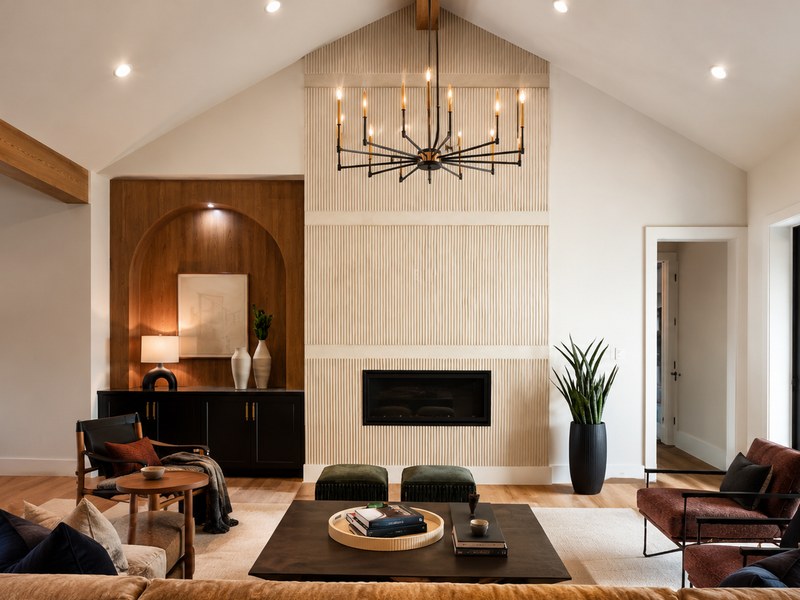A cream fluted fireplace wall, wood cabinetry and a hanging chandelier in a Color Unlimited Painting interior.