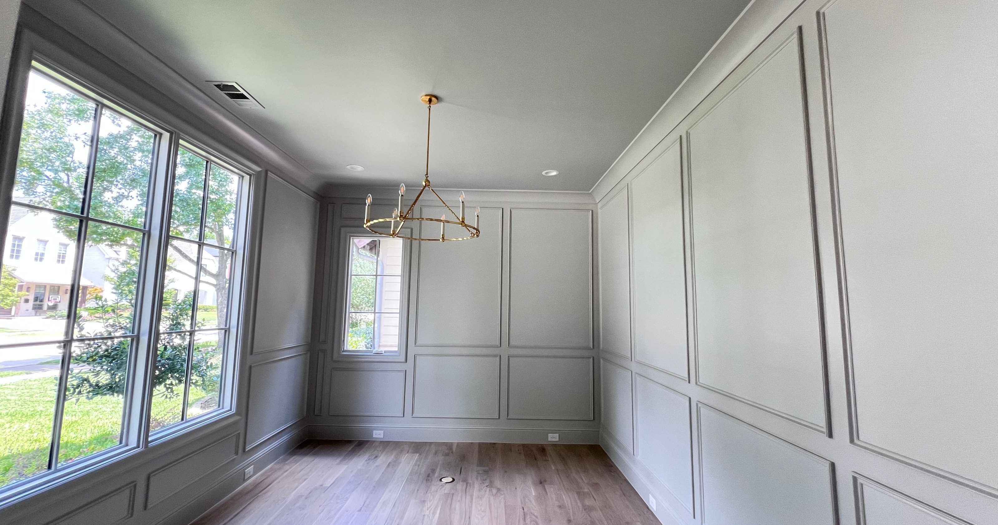 Finished interior room with pale paneled walls, a white ceiling, wood floor and tall windows.