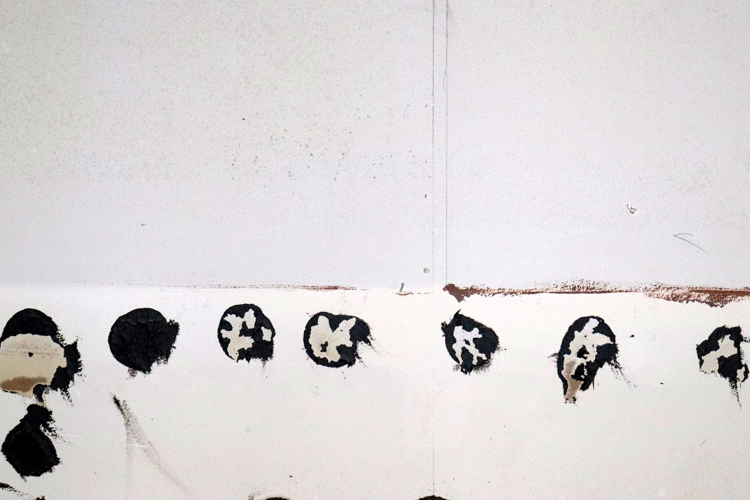 Wall surface with torn facing, dark marks and a horizontal scar before repair.