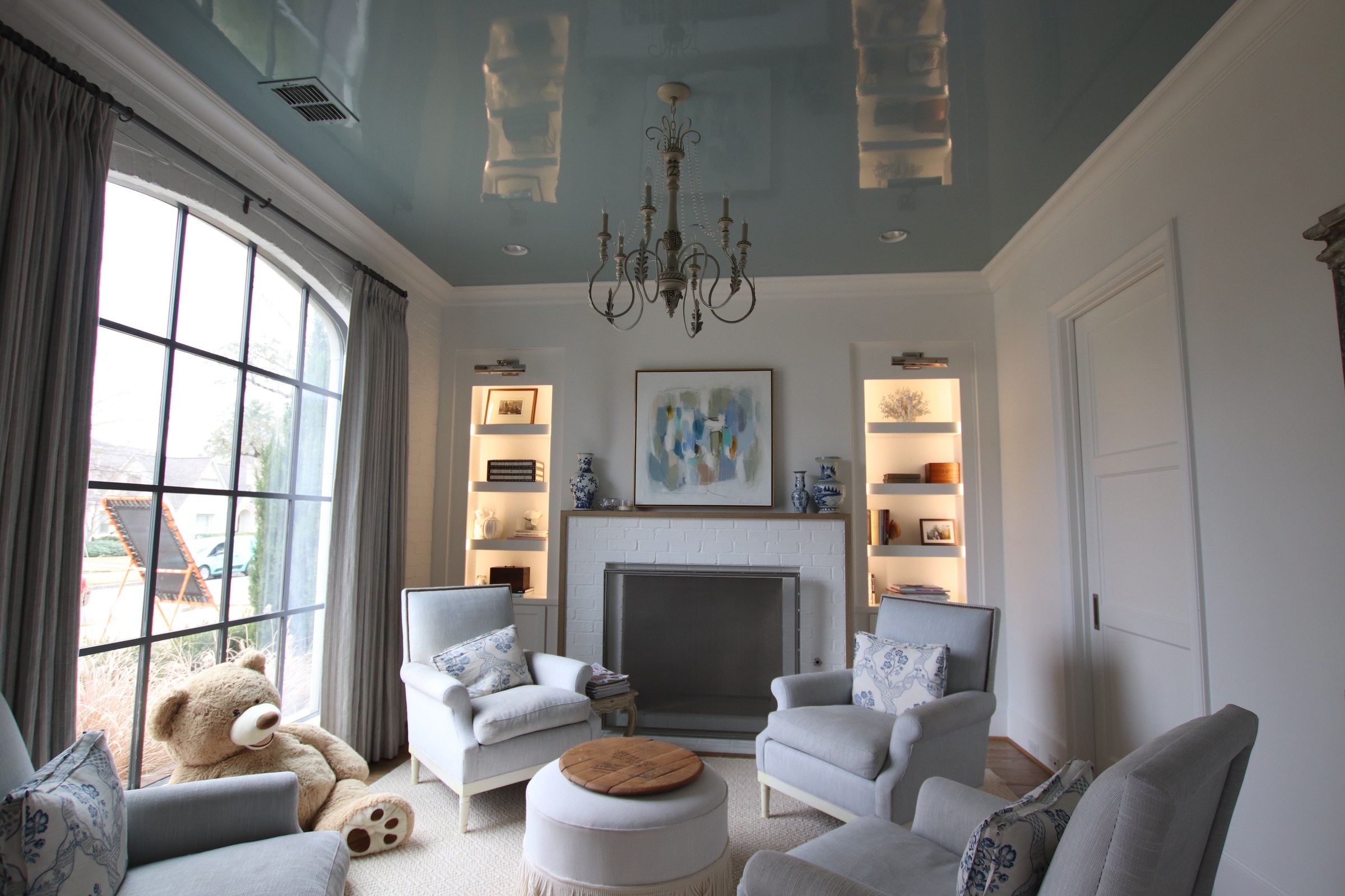 Blue high-gloss ceiling above a furnished sitting room with white trim, fireplace, and teddy bear.