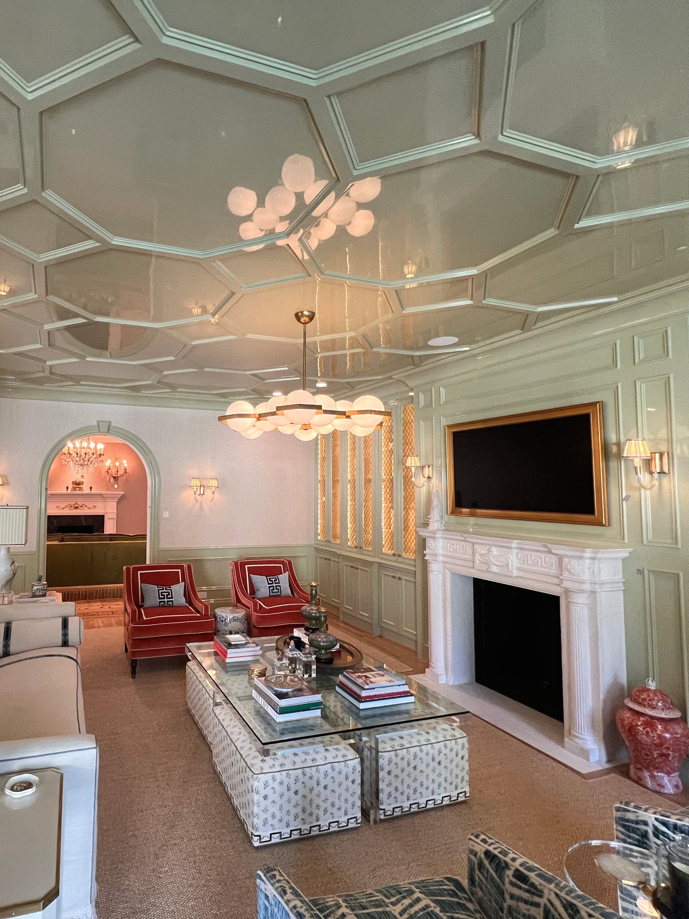 High-gloss paneled ceiling and pale millwork above a furnished living room.