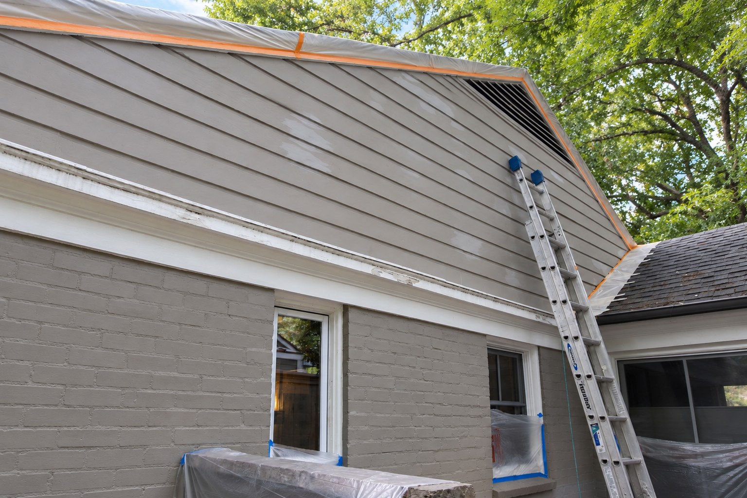 Gray siding and masonry during exterior preparation.