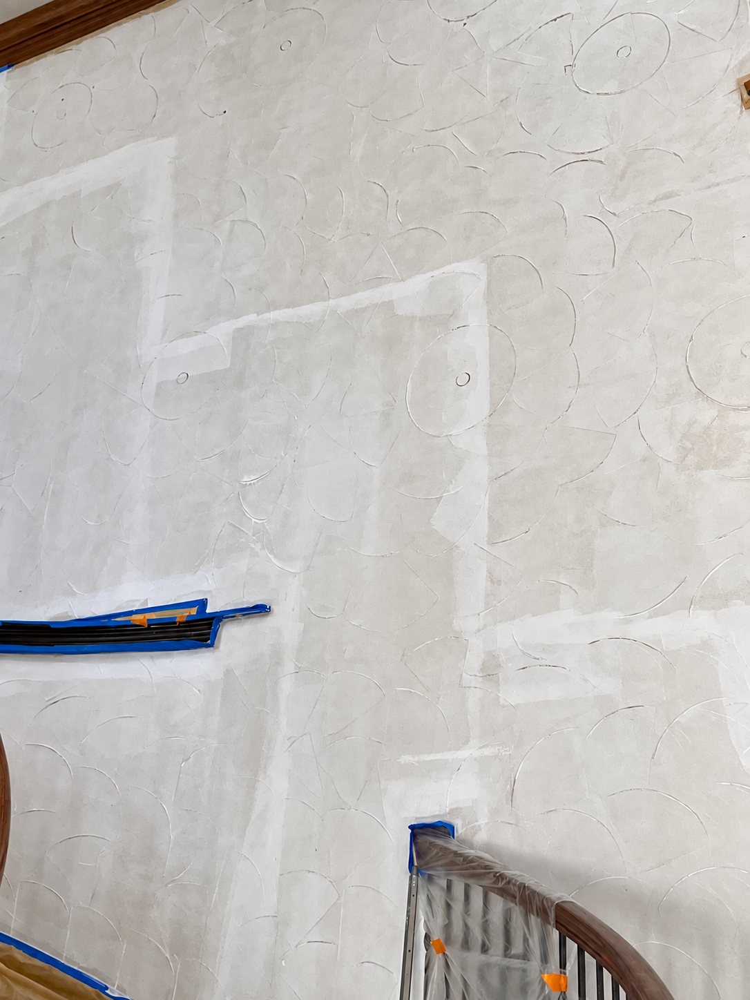Stairwell wall during surface preparation with trim and railing protected.